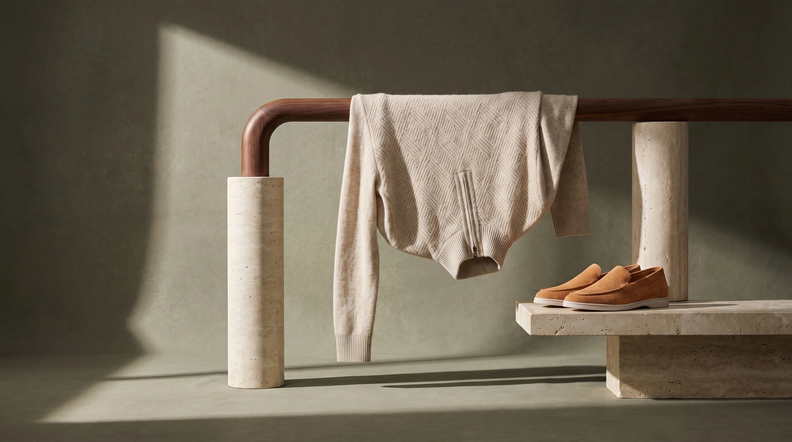 Cream Merino knit and tan suede loafers arranged on a sculptural walnut and stone display